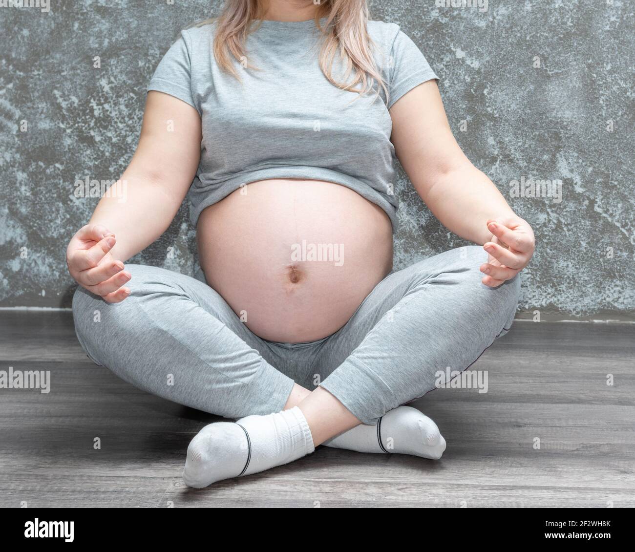 Mujer embarazada meditando en casa, practicando yoga. Joven feliz expectante relajante, pensando en su bebé y disfrutando de su vida futura. Maternidad, Foto de stock