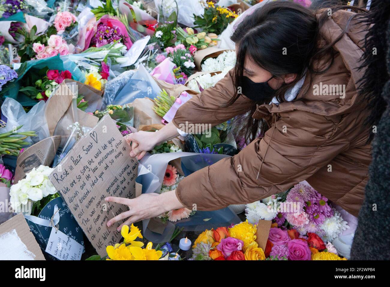 Londres, Reino Unido, 13 de marzo de 2021: Un monumento a las flores de Sarah Everard atrae a cientos de personas que se marchan bien en el bandstand de Clapham Common. Los tributos incluían plantas, flores, velas y mensajes como "¿Cuándo estarán seguras las mujeres?" Y 'solo estaba caminando a casa.' Una vigilia oficial ha sido cancelada debido a las preocupaciones de la policía por el coronavirus. Anna Watson/Alamy Live News Foto de stock