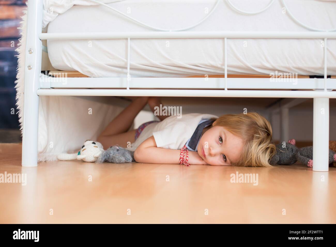 Niño pequeño, escondido bajo la cama con juguetes rellenos, asustado de  monstruos de pesadilla Fotografía de stock - Alamy