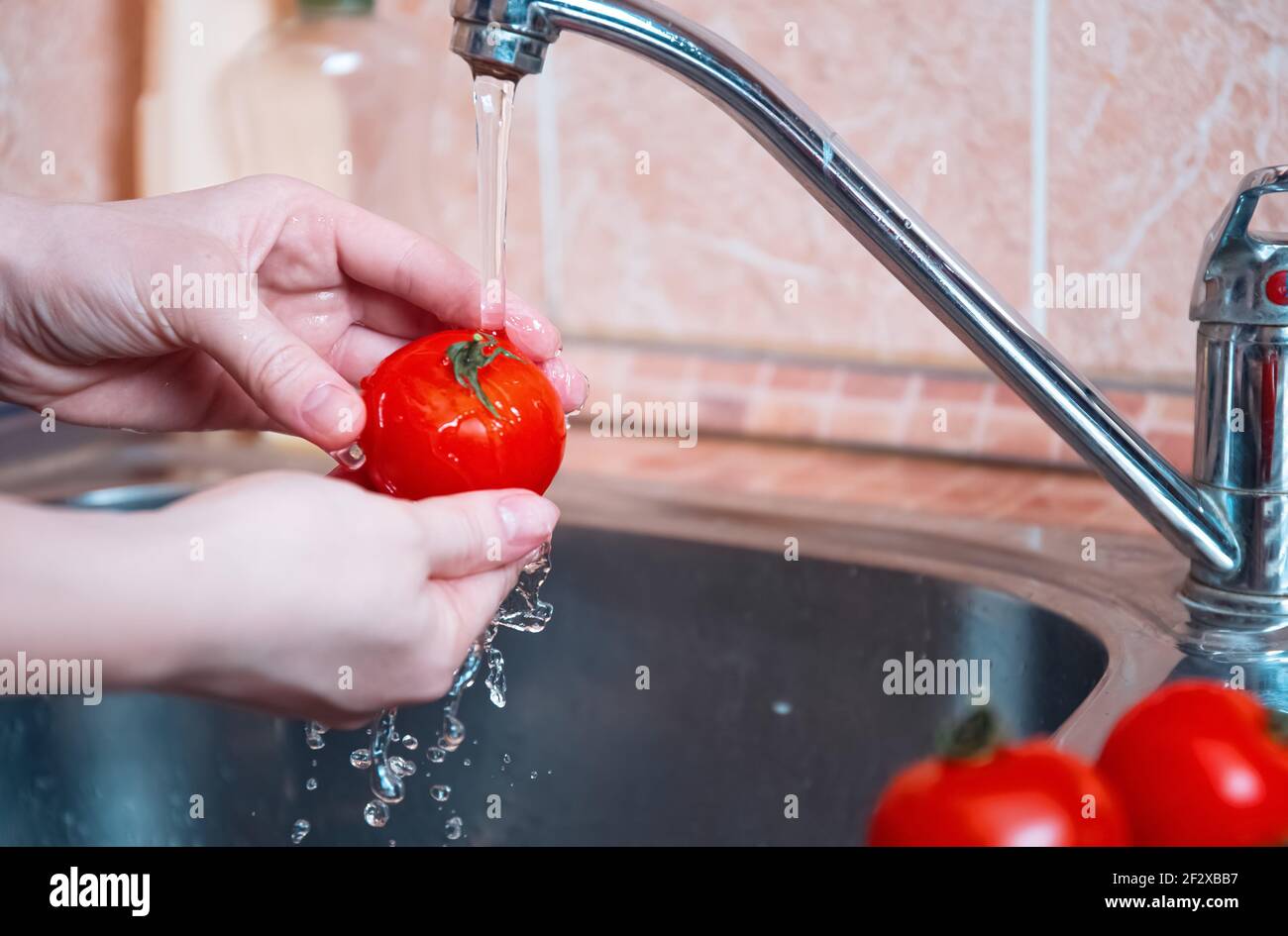 lavado de verduras. Las mujeres lavan las verduras en las manos antes de cocinarlas bajo el agua corriente. Higiene personal Foto de stock