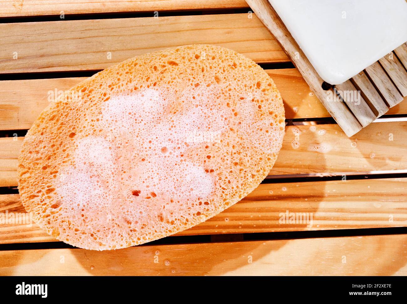 Esponja de baño naranja con burbujas sobre fondo de madera, en el fondo  jabón blanco Fotografía de stock - Alamy