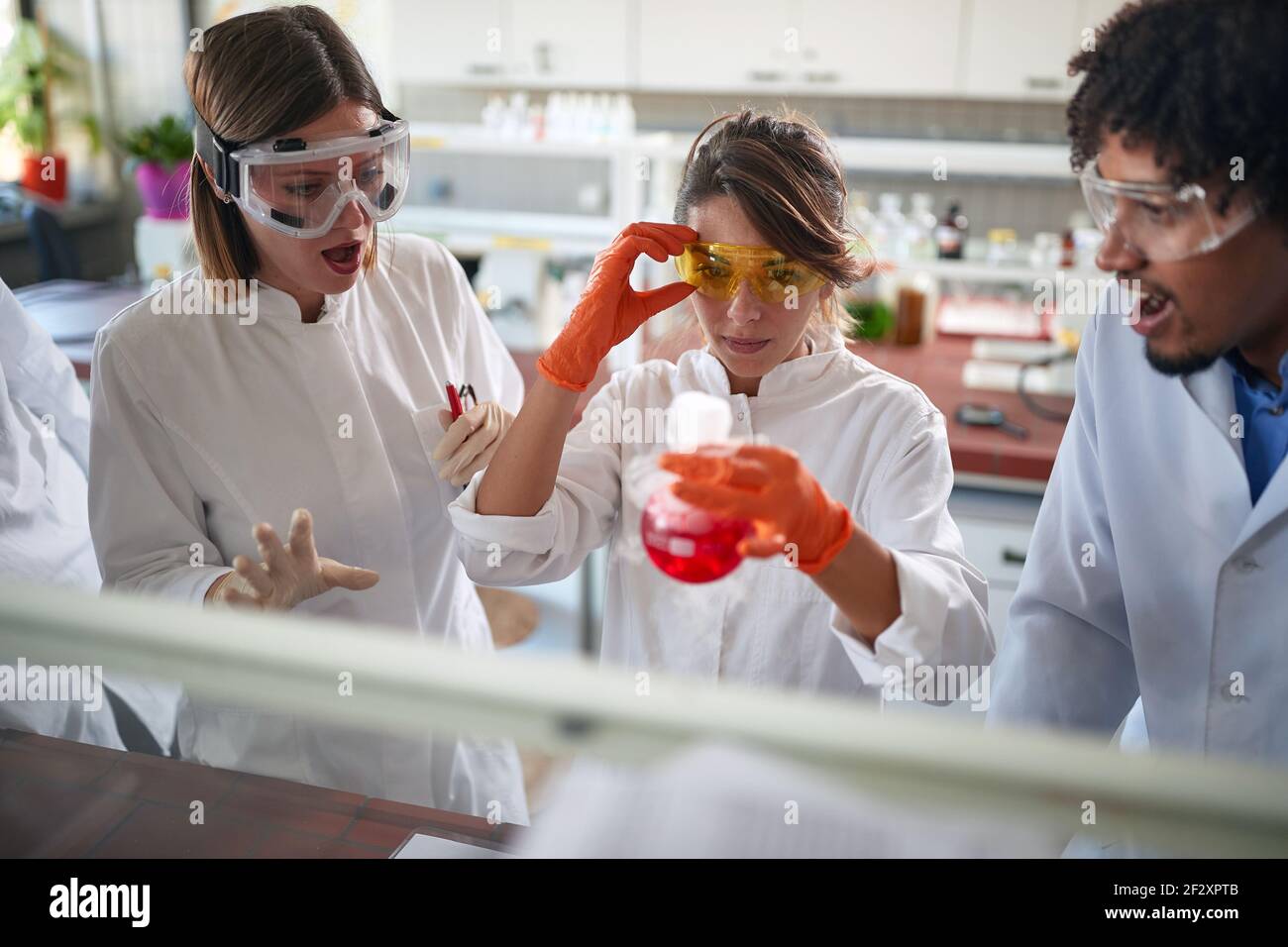 Jóvenes estudiantes de química excitada están observando una reacción química en un experimento que hacen en un laboratorio en una atmósfera de trabajo. Ciencia, química Foto de stock