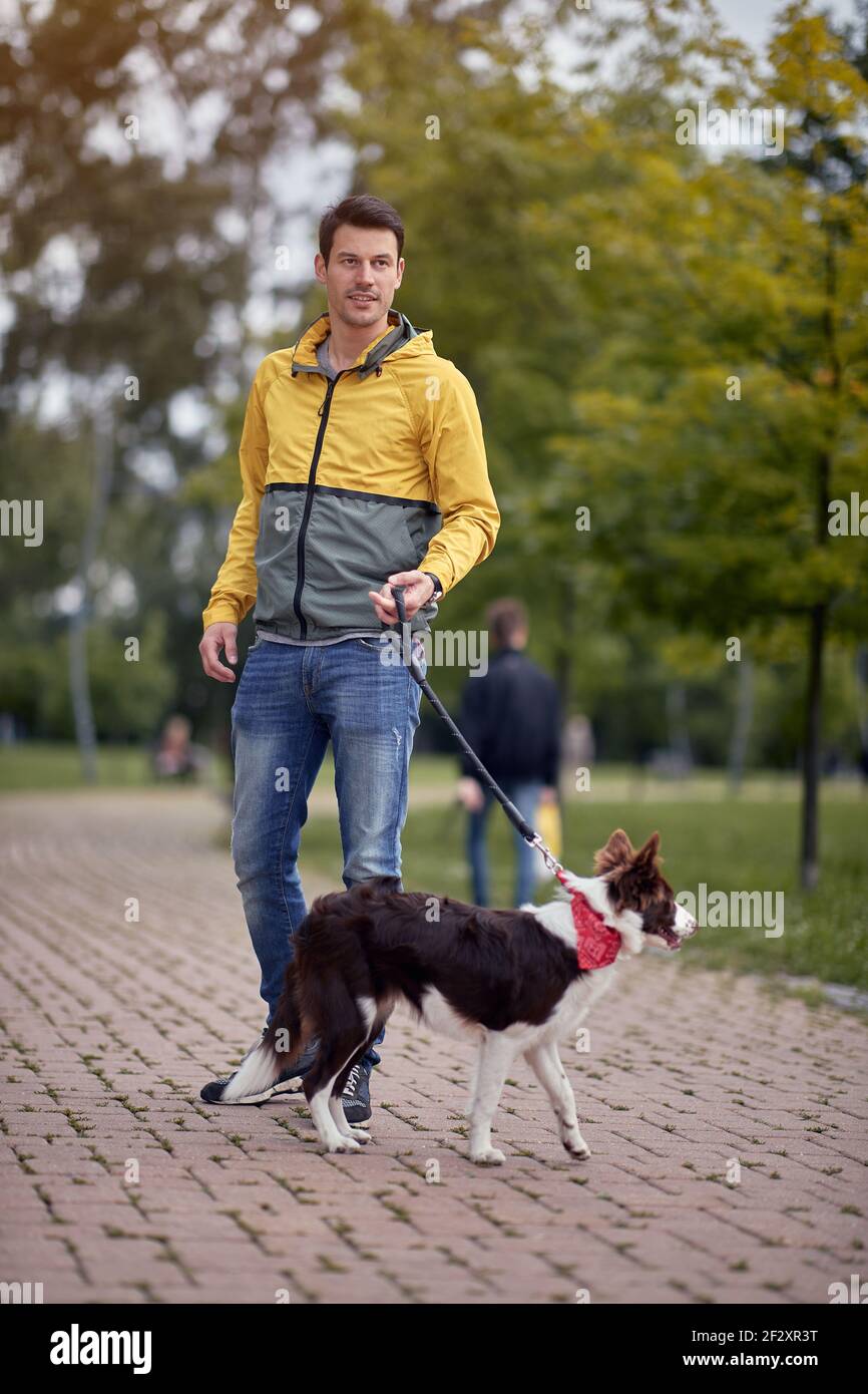un joven caucásico caminando a su perro en una correa hermoso parque de otoño Foto de stock