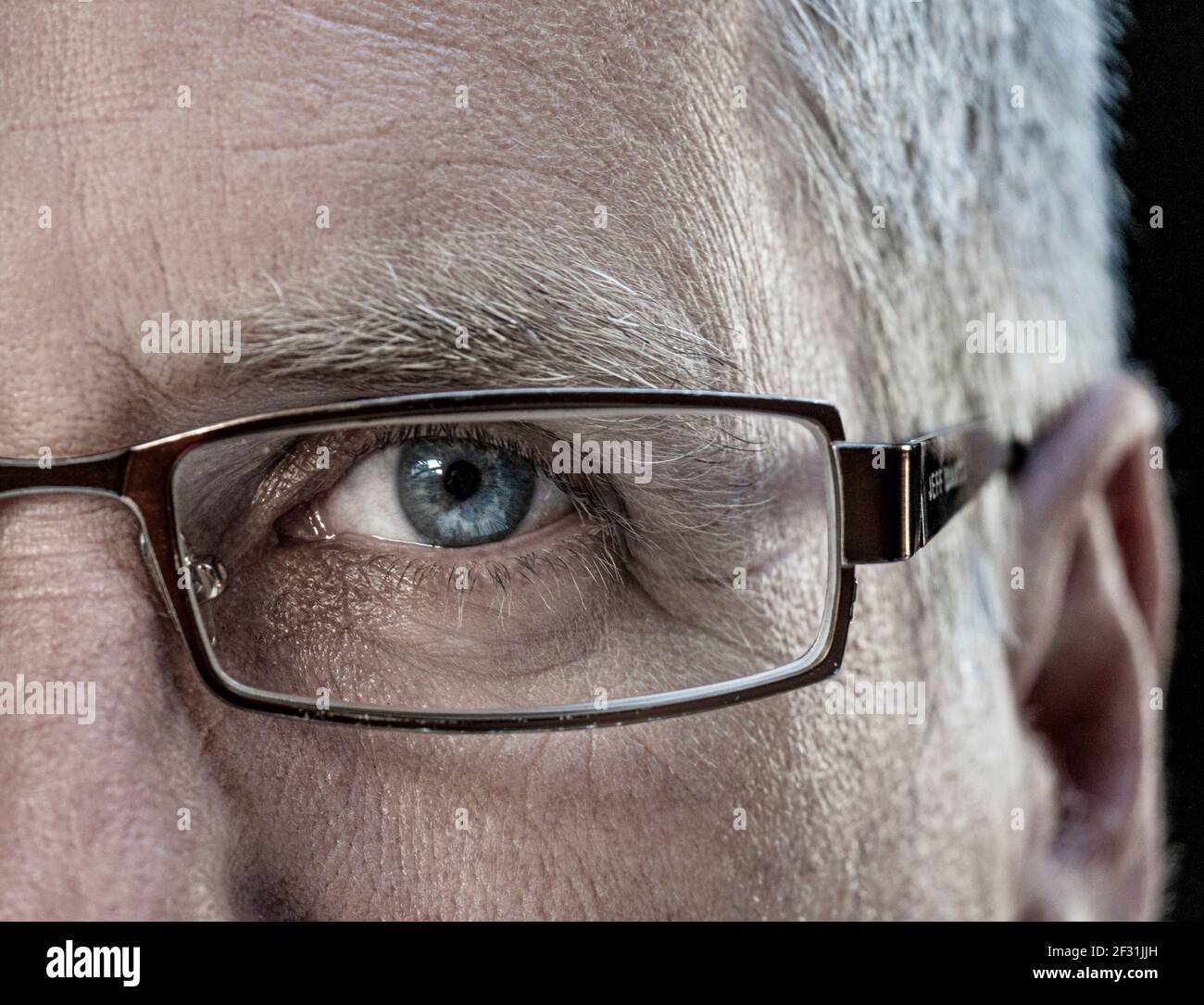 Hombre medio rostro gafas ojo hombre maduro edad 50-55 años con gafas de diseño, las gafas se acercan a la vista de ojos azules orientación directa hacia delante Foto de stock