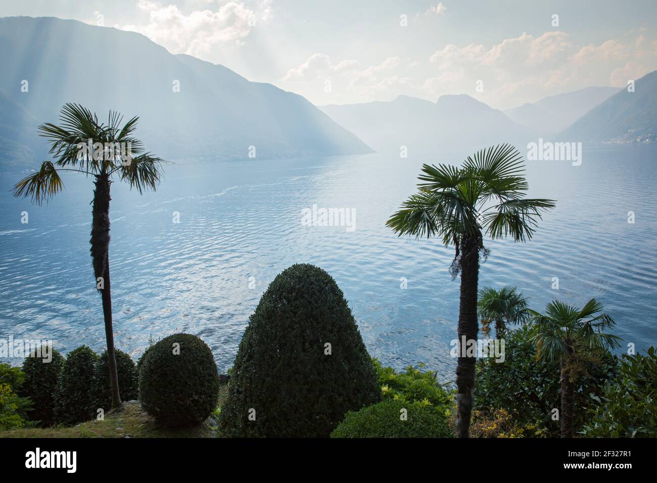 Italia, Lombardía, Lenno, vista al lago Como con montañas y palmeras desde Villa del Balbianello Foto de stock