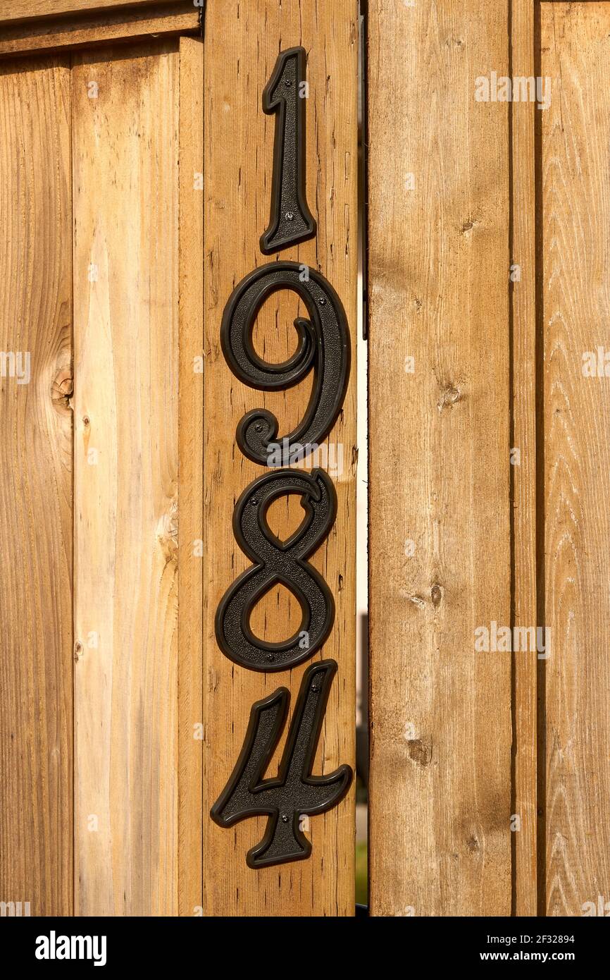 Cierre de metal 1984 número de casa sobre valla de madera Foto de stock