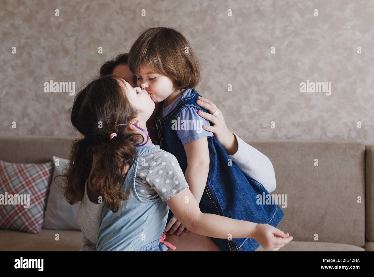 dos chicas se besan unas a otras en los labios mientras sentado en el  regazo de su madre Fotografía de stock - Alamy