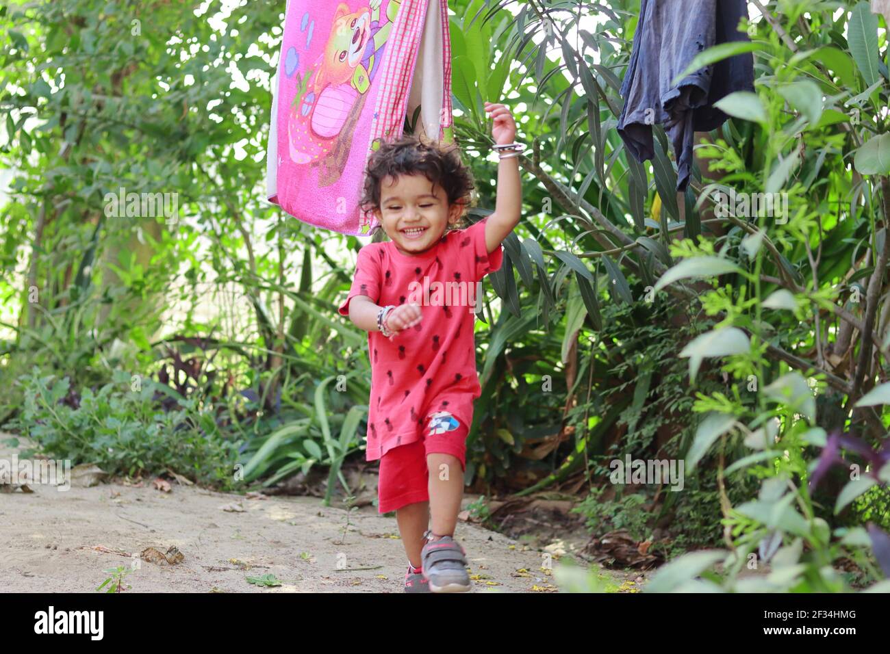 un niño de origen indio que salta y juega en el jardín, india.Concept para las alegrías de la infancia, recuerdos de la infancia, expresiones de la cara del bebé y cuerpo Foto de stock