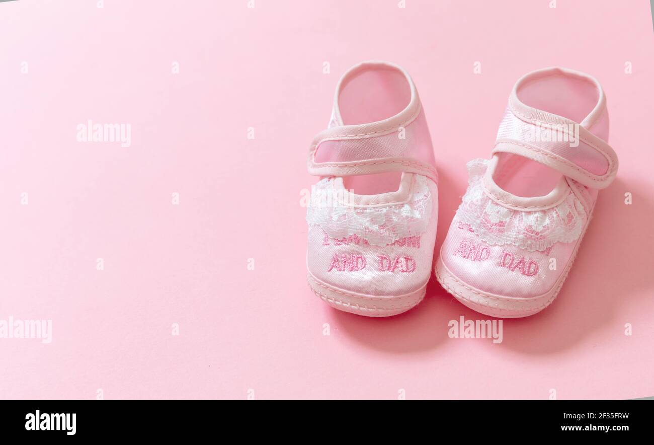 La ducha del bebé, el concepto del bautizo de la muchacha. Zapatos rosa bebé  sobre fondo de color rosa. Es una plantilla de anuncio de recién nacido  niña. Bebé mujer suave footwea