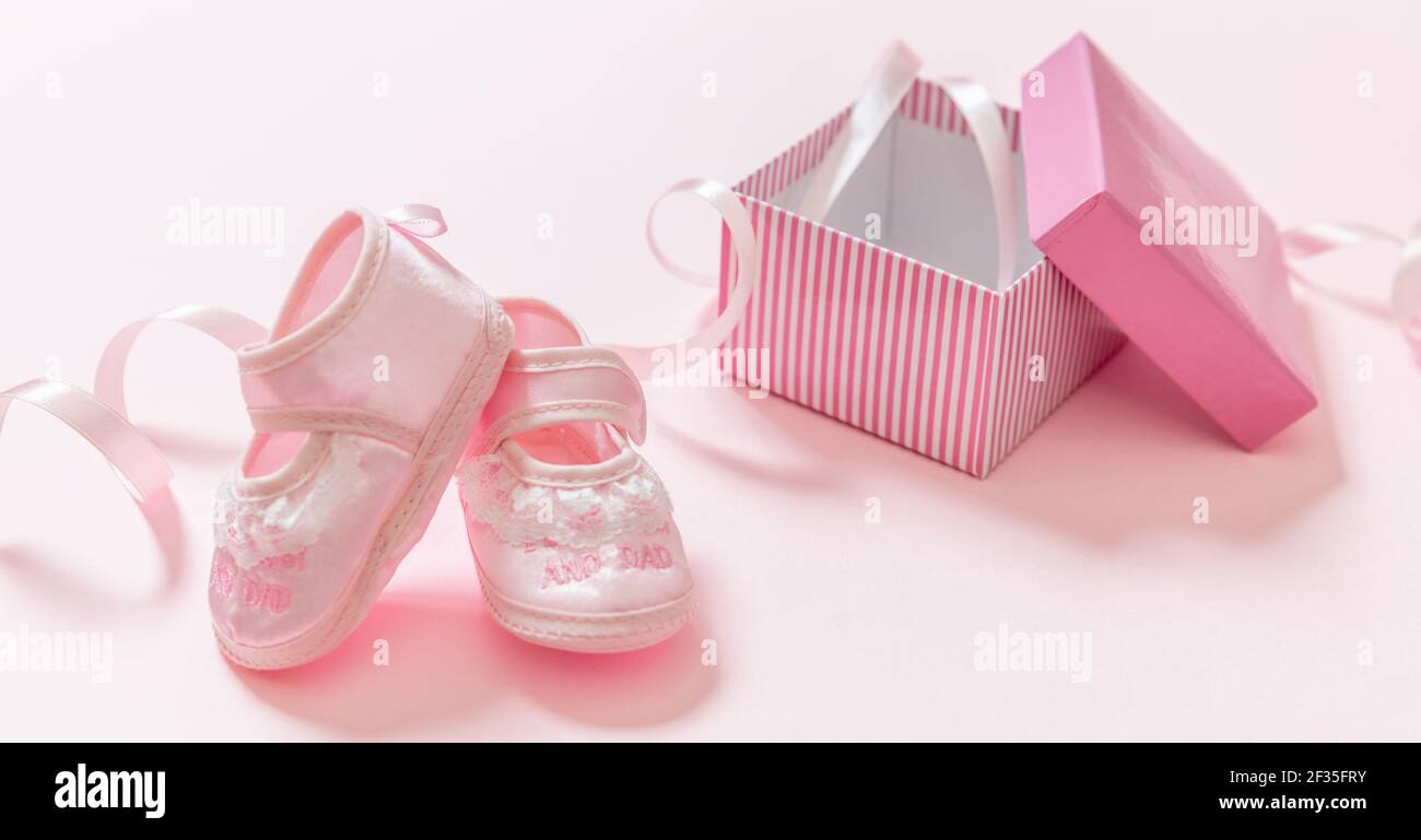 Zapatos rosa bebé fondo de color rosa. Es una plantilla de anuncio de recién nacido niña. Calzado femenino suave para bebés de una de regalo abierta. Bebé showe Fotografía de