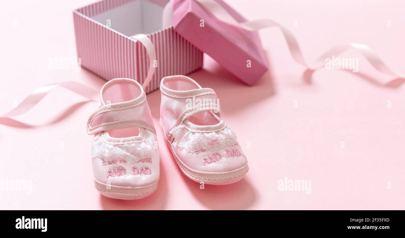 Zapatos rosa bebé de una caja de regalo abierta. La ducha del bebé, el concepto del bautizo de la muchacha. Calzado femenino suave para bebés sobre fondo de color rosa. Es