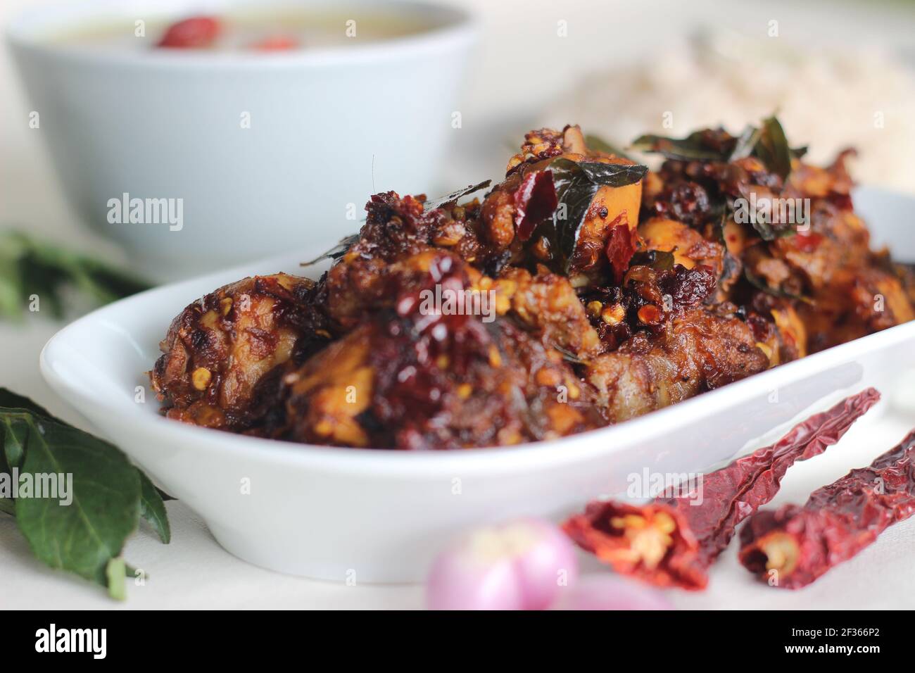 Chicken casero preparado en estilo desi con 5 ingredientes. Una receta simple de pollo con chiles rojos enteros, chalotas, hojas de curry, coco oi Foto de stock