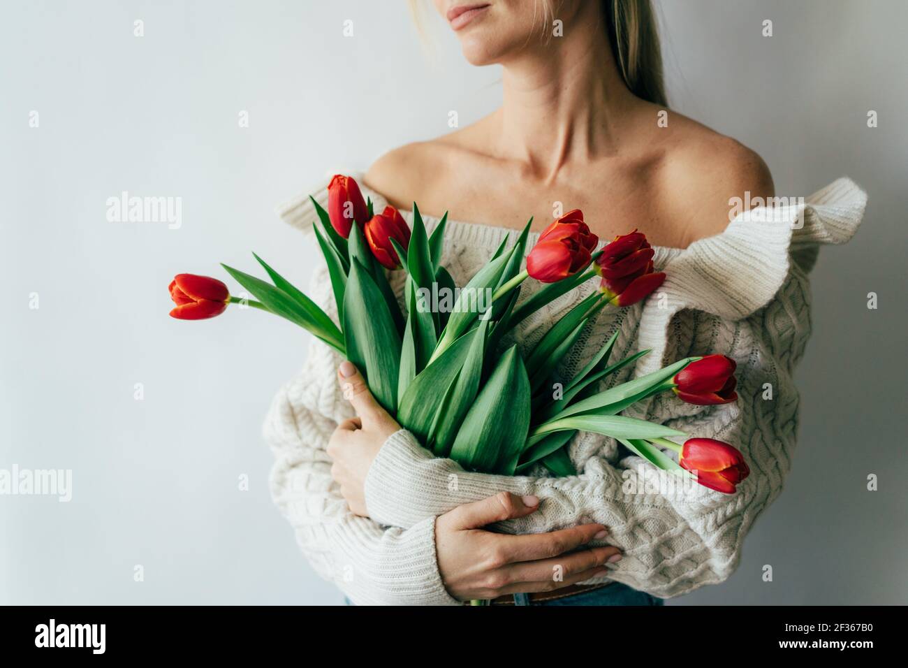 Una mujer joven sostiene un hermoso ramo de tulipanes rojos en sus manos. Foto de stock