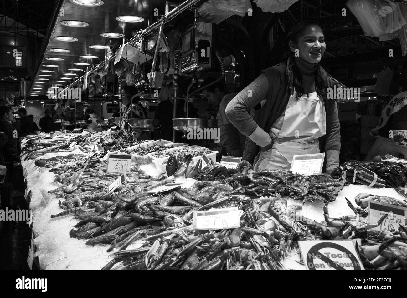 BARCELONA, ESPAÑA - 10 DE MARZO de 2018: Famoso mercado de comida de Barcelona la Boqueria. Mariscos y pescados puestos. Joven vendedor sirviendo a los clientes con una sonrisa. Foto de stock