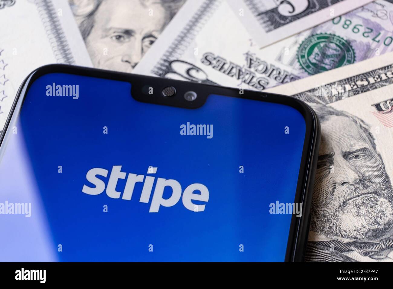 Sitio web del proveedor de pago Stripe visto en la esquina del smartphone colocado en las facturas del dólar. Stafford, Reino Unido, 14 de marzo de 2021. Foto de stock