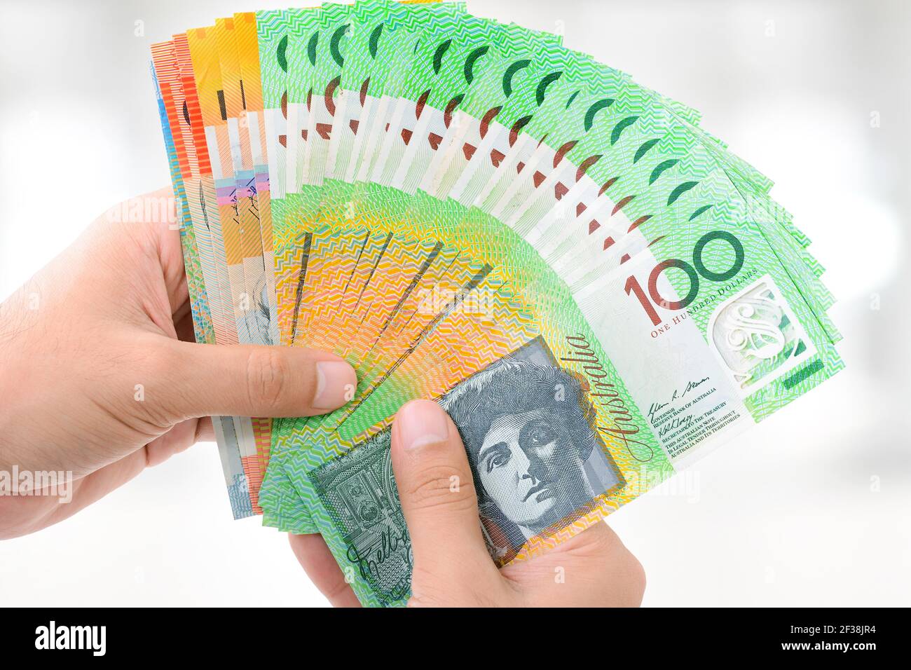 Manos con dinero, billetes en dólares australianos (AUD), sobre fondo blanco gris Foto de stock