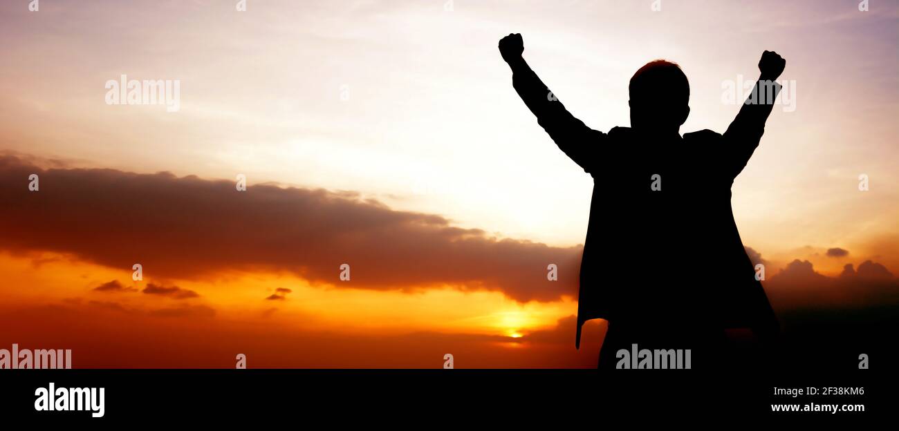Silueta de un hombre levantando sus brazos en el cielo crepúsculo fondo panorámico (o cabecera) - éxito, ganar y conceptos consumados Foto de stock