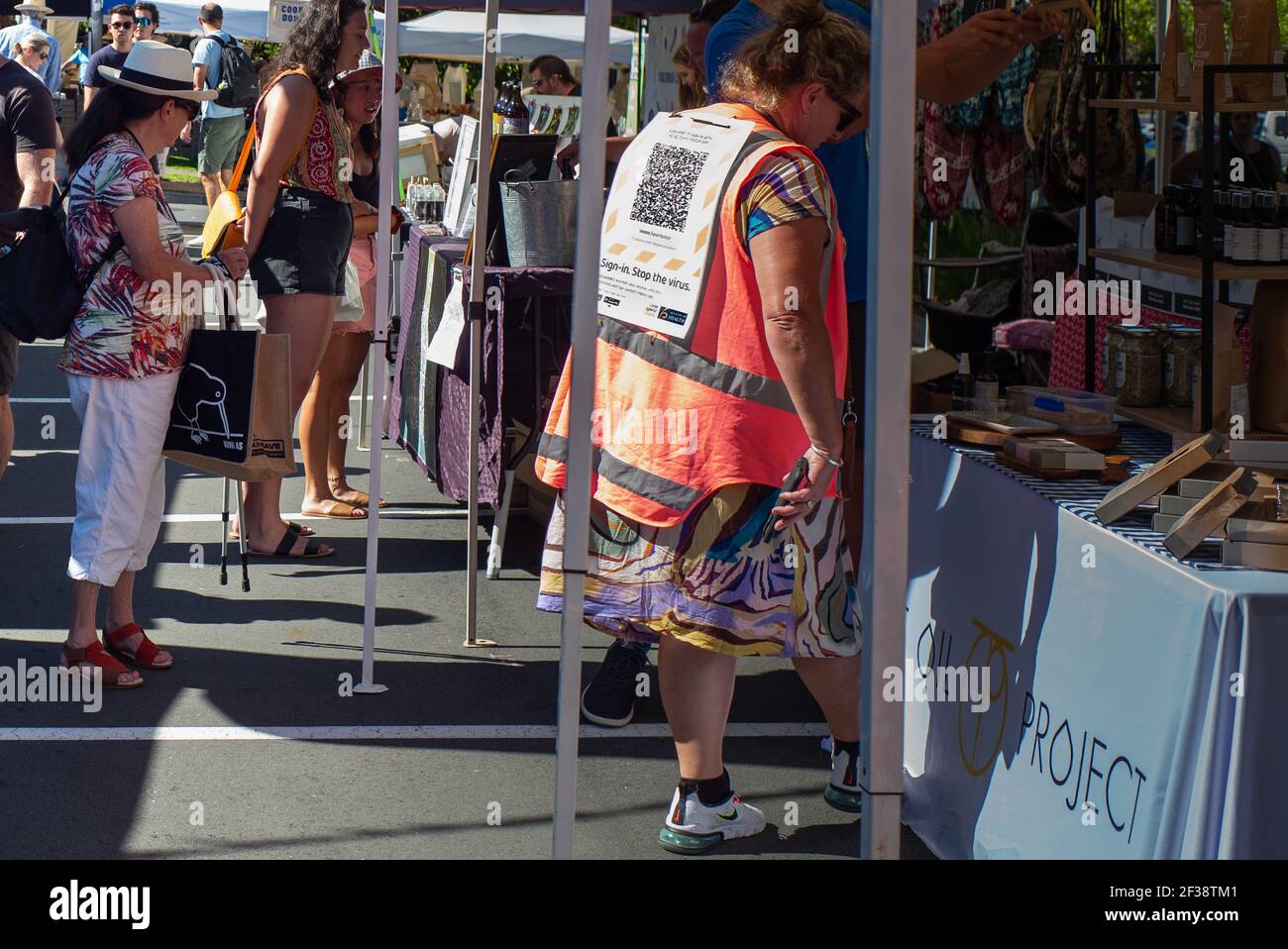 Mujer con código QR Covid-19 mira un puesto en el Mercado Domingo de la Granja Smachos, Takapuna, Auckland Foto de stock