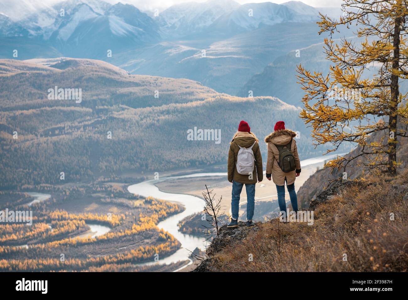 Dos niñas viajeros están de pie en el acantilado y mira a las montañas y el río. Concepto de montaña de viajes Foto de stock