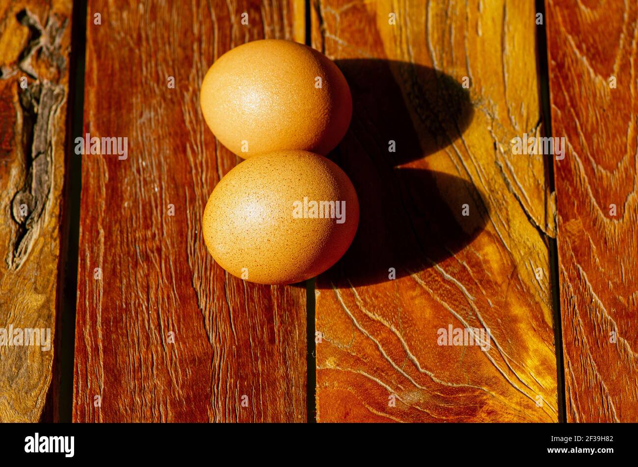 Dos huevos de pollo en la vieja mesa de teca, vista superior en enfoque poco profundo Foto de stock