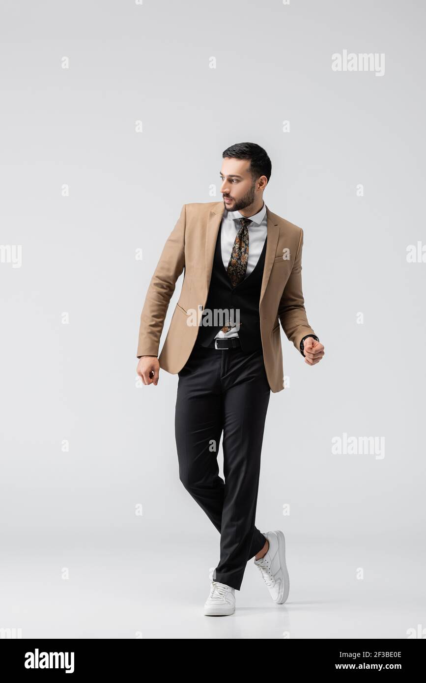vista completa del joven musulmán con ropa elegante y zapatillas de deporte  de pie en gris Fotografía de stock - Alamy