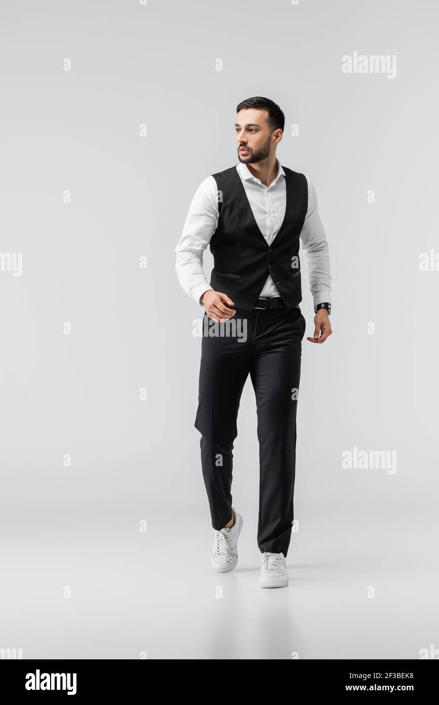 vista completa del hombre de moda con ropa y zapatillas deporte caminando sobre gris Fotografía de stock - Alamy