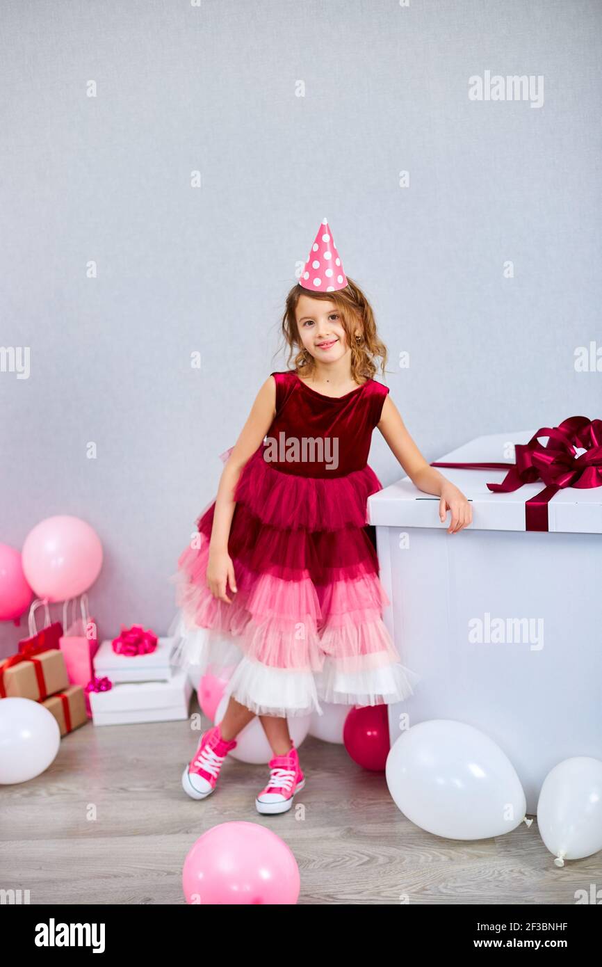 Alegre niña en vestido rosa y zapatillas de deporte con gran caja de regalo  presente, globos en casa cumpleaños fiesta streamers, Feliz cumpleaños.  Celebrando Fotografía de stock - Alamy
