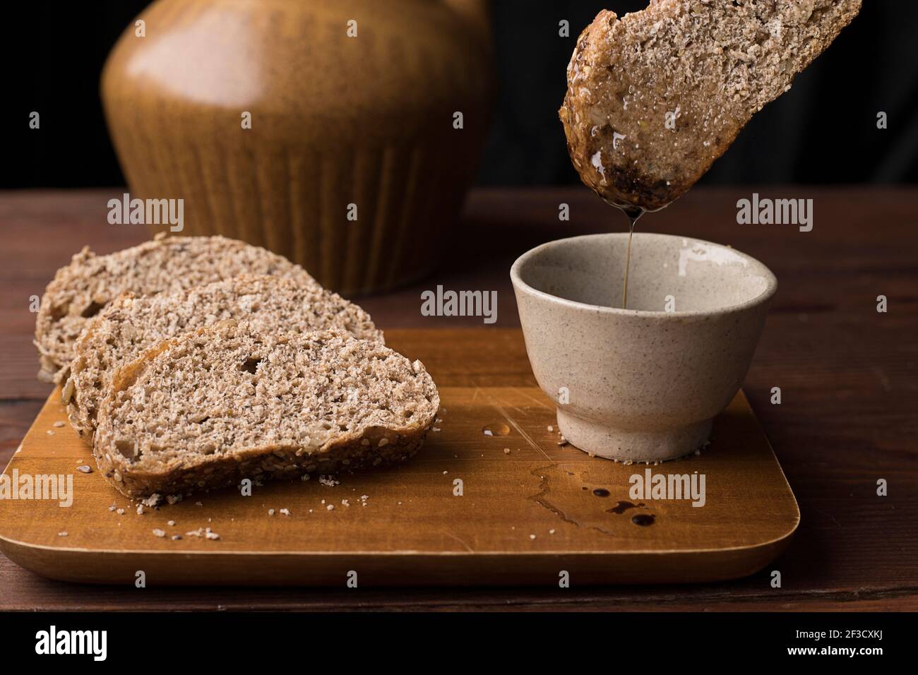 Una foto de estudio de sumergir una rebanada de pan de trigo en aceite y vinagre balsimico. Foto de stock