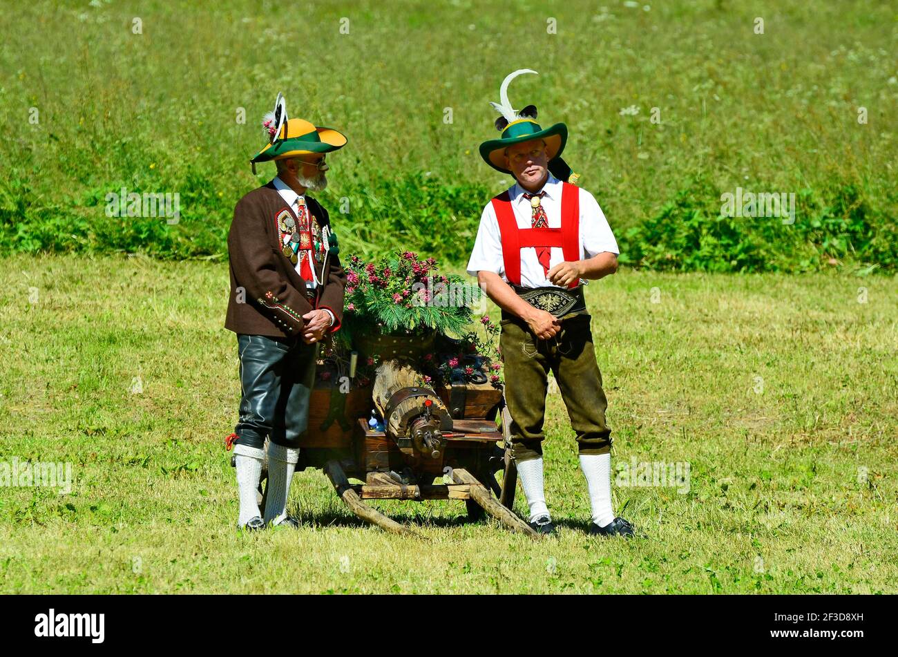Feichten, Austria - 22 de junio de 2014: Dos hombres no identificados en traje tradicional con armas saltando armas de fuego por masa de campo en el Tirol Foto de stock