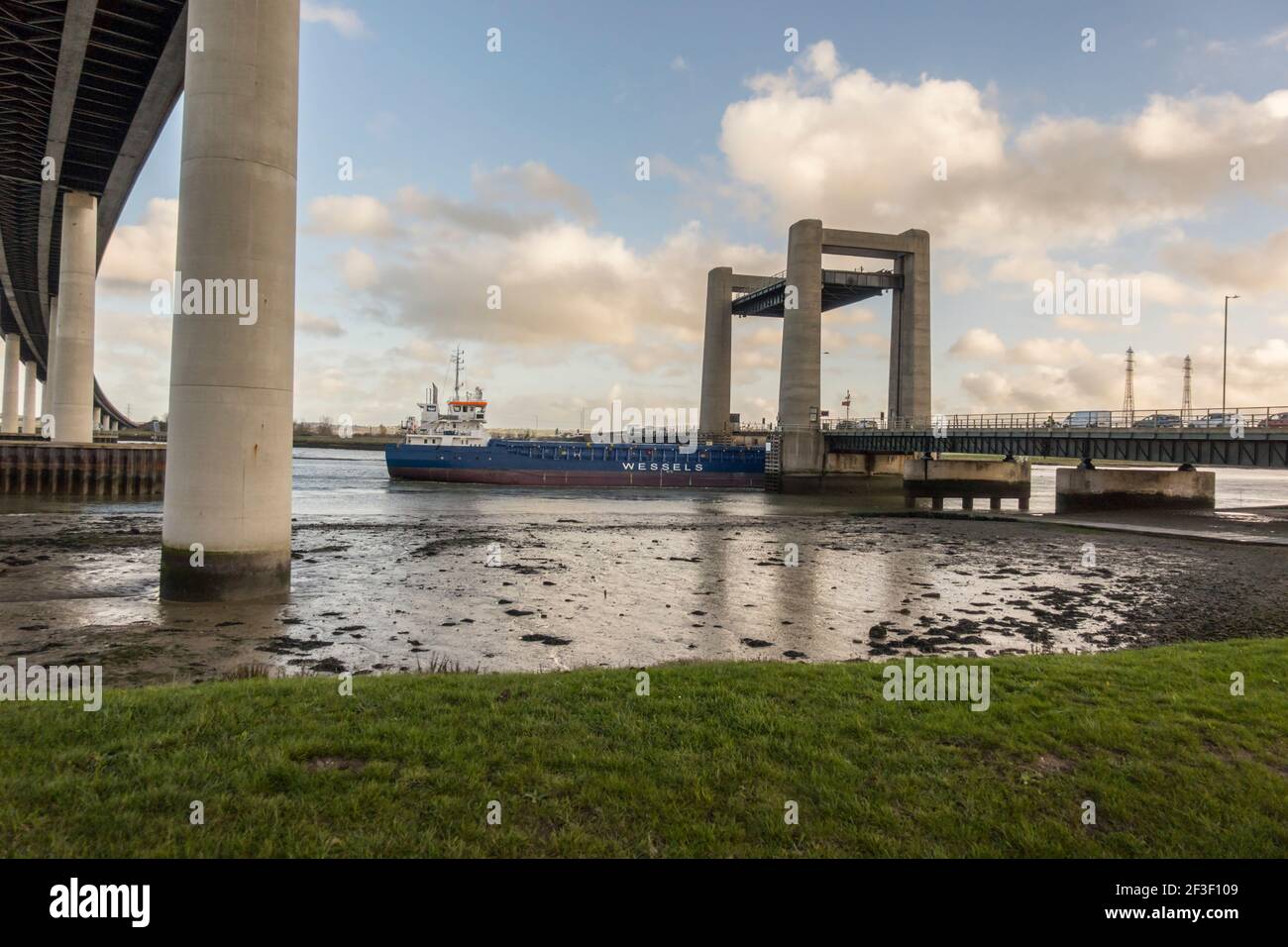 El barco pasa a través del puente Kingsferry que une la isla de Sheppey y Kent a través del Swale. Desde debajo del nuevo puente Sheppey Foto de stock