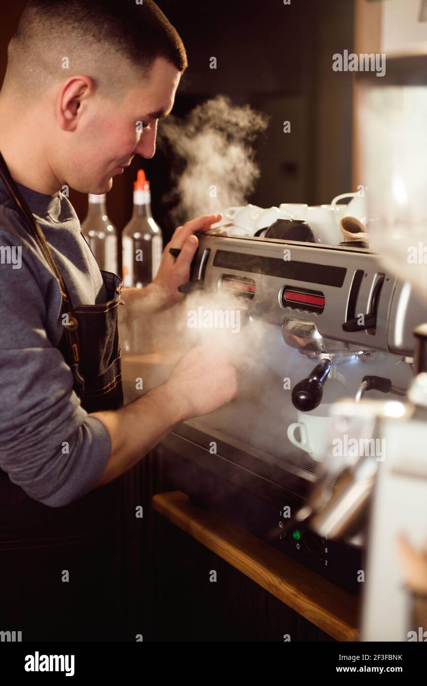 Sonriente barista macho utilizando máquina de café profesional disfrutando  de trabajo en café mejorar las habilidades de hacer capuchino Fotografía de  stock - Alamy