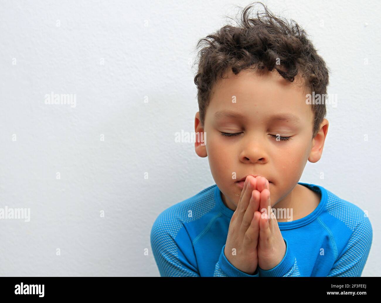Niño Orando A Dios Con Las Manos Sostenidas Junto Con Cerrado Ojos En