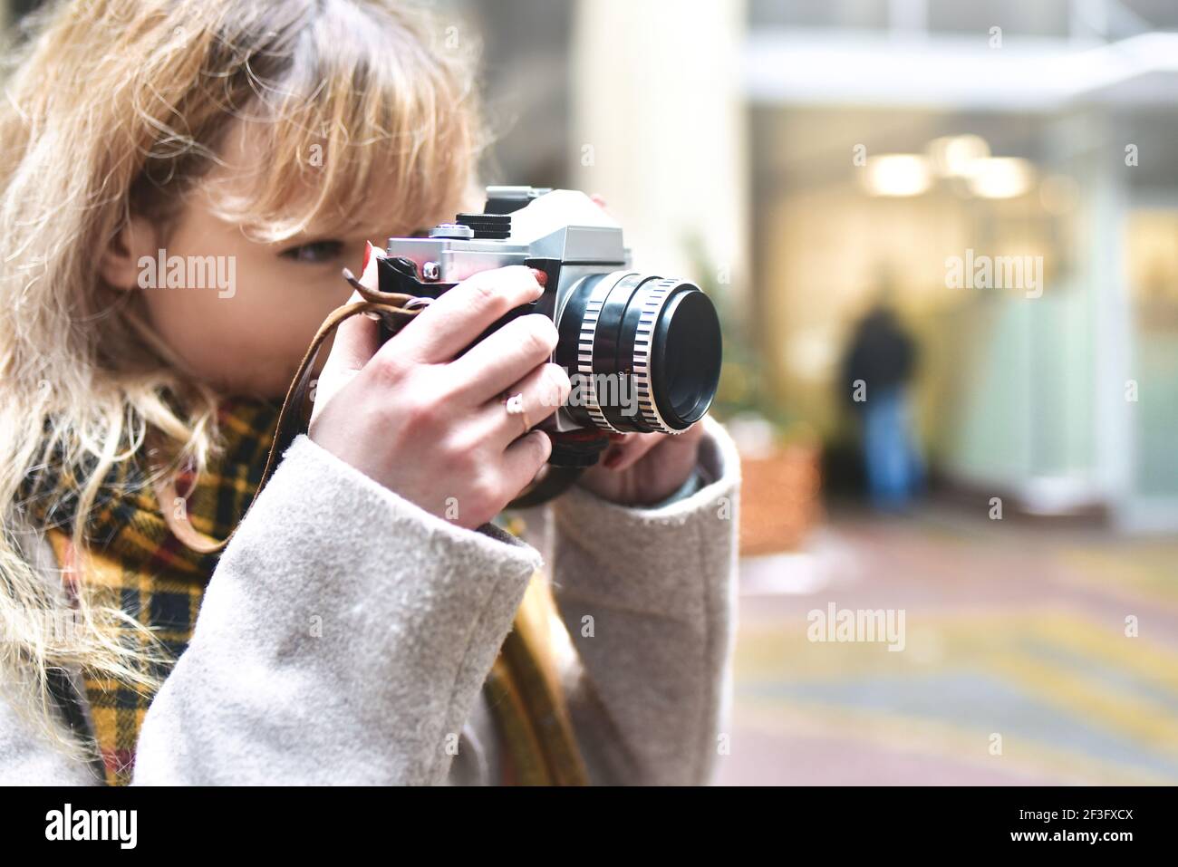 Rubia bonita fotógrafa mujer con cámara retro en sus manos mientras toma fotos en la antigua arquitectura urbana. Descubre nuevos lugares. Foto de stock