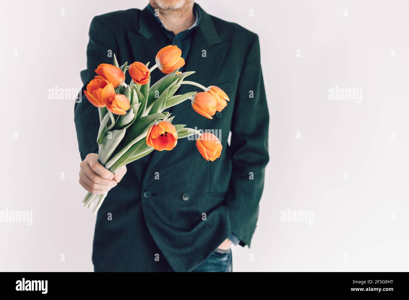 Un hombre sostiene un ramo de flores delante de él. Tulipanes de 