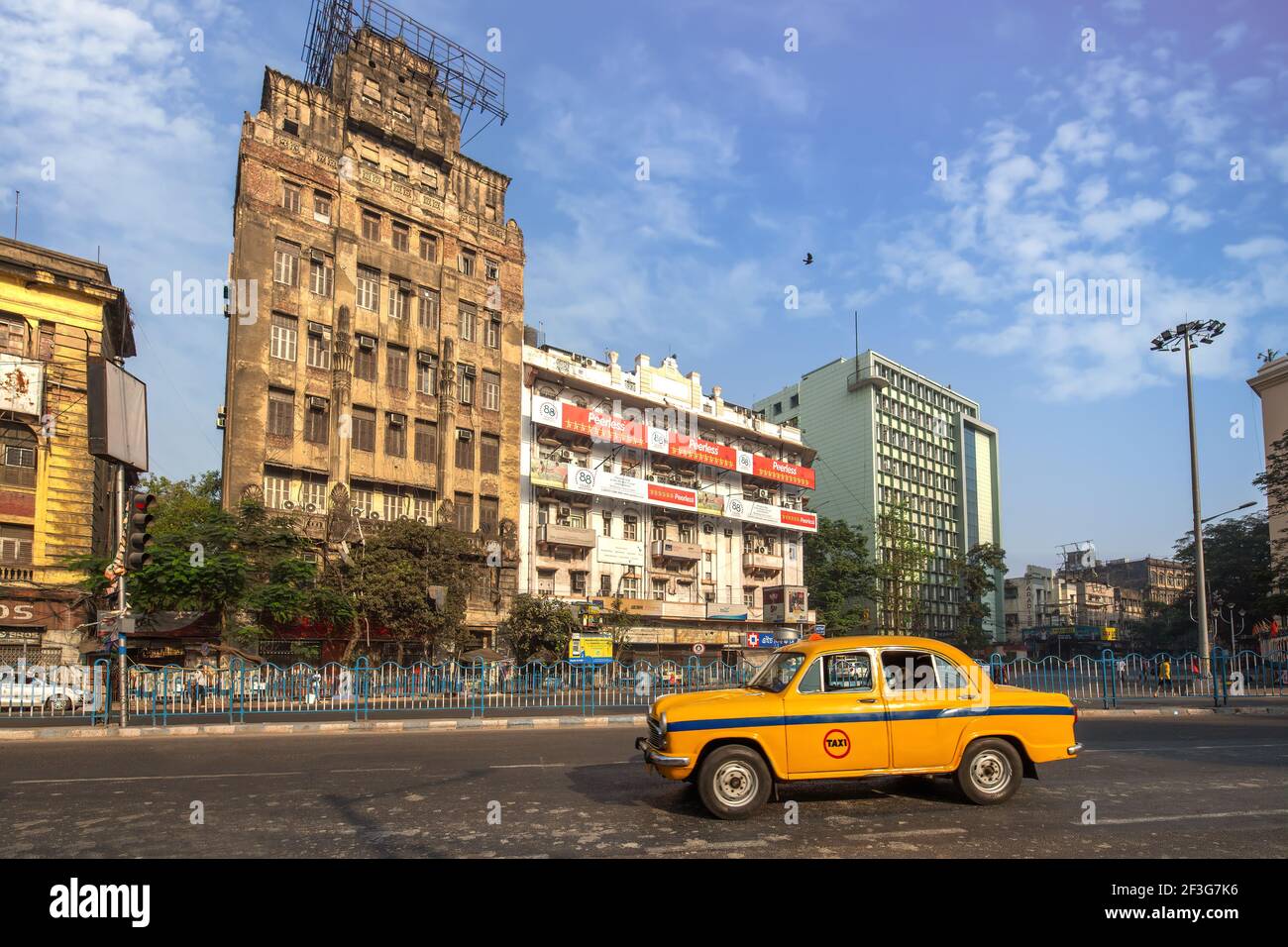 Taxi amarillo en la carretera de la ciudad con vistas a los edificios de oficinas En la zona de Esplanade de Kolkata Foto de stock