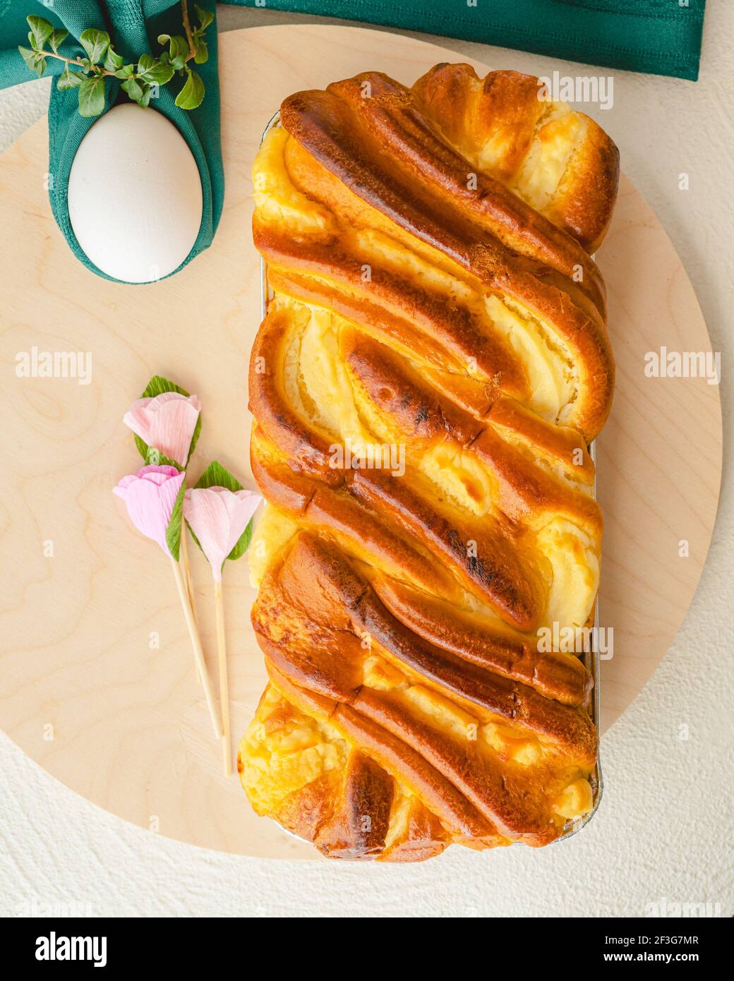 Pastel de levadura horneado con queso crema, huevos blancos de cerca en tabla de servir de madera, laico plano, pancarta vertical. Brioche y huevos. Primavera, Foto de stock