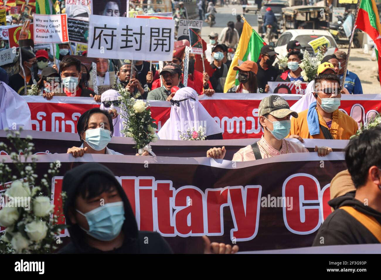 Muse, Estado de Shan del Norte, Myanmar. 13th de febrero de 2021. Los manifestantes contra el golpe militar tienen varias banderas grandes durante una manifestación pacífica contra el golpe militar.UNA muchedumbre masiva tomó las calles de Muse (ciudad fronteriza birmana con China) para protestar contra el golpe militar y exigió la liberación de Aung San Suu Kyi. Los militares de Myanmar detuvieron a la Consejera de Estado de Myanmar Aung San Suu Kyi el 01 de febrero de 2021 y declararon un estado de emergencia mientras se apoderaban del poder en el país durante un año después de perder las elecciones contra la Liga Nacional para la Democracia (imagen de crédito: © Mine SMI Foto de stock