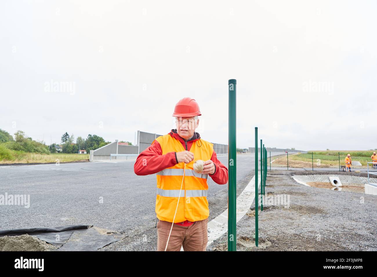 Trabajadores en el lugar de construcción en la construcción de carreteras en el nueva carretera de circunvalación en la valla Foto de stock