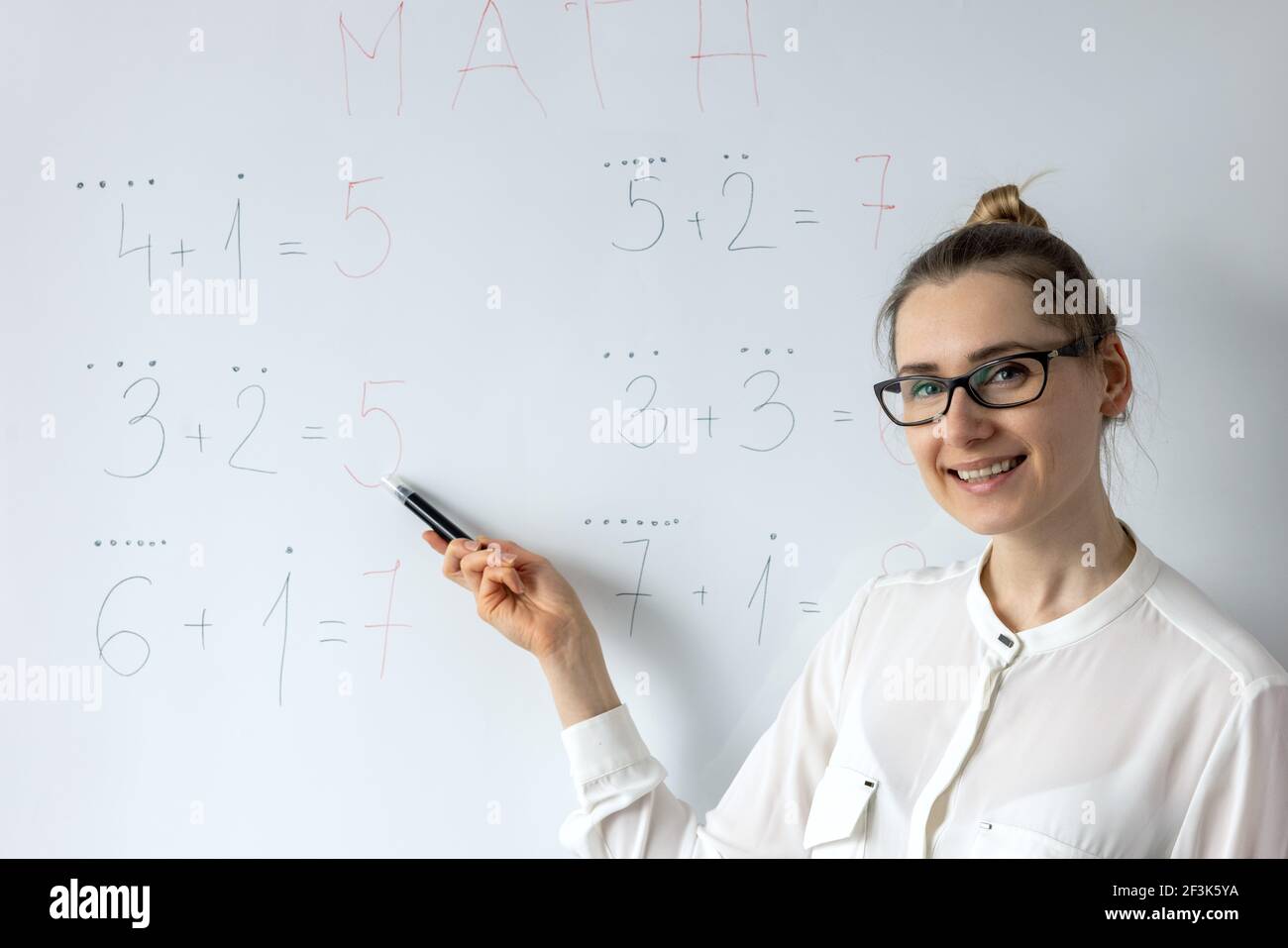 maestro de matemáticas explicando matemáticas básicas de la escuela primaria en la pizarra blanca aula Foto de stock