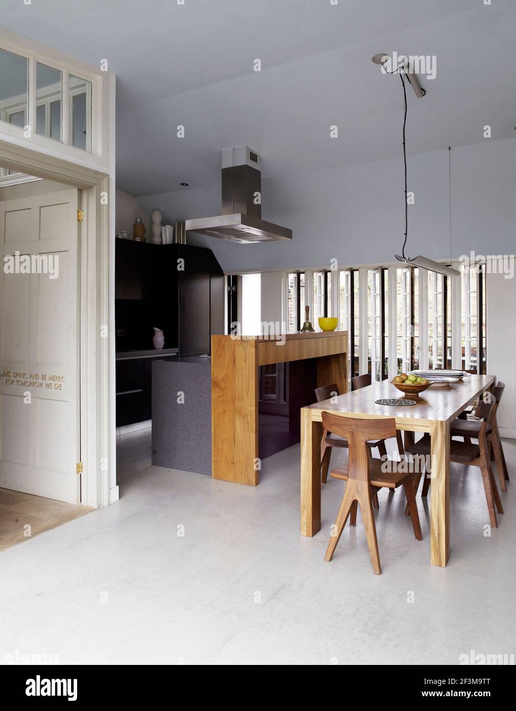 Cocina de planta abierta y comedor con mesa y sillas, luz colgante y ventilador extractor en casa residencial, Reino Unido. Foto de stock