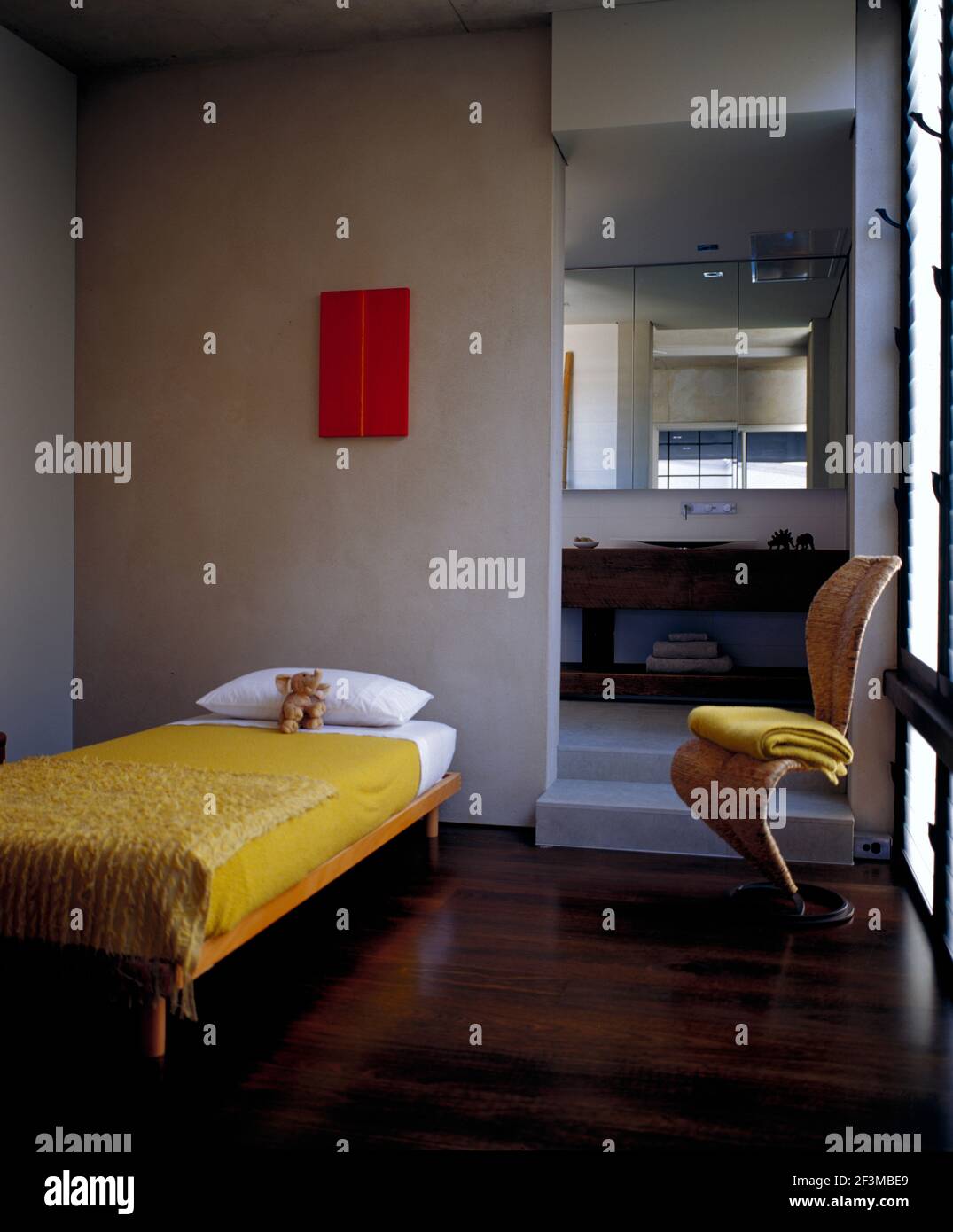 Dormitorio con cama individual y silla con puerta abierta al baño en casa residencial, Australia Foto de stock
