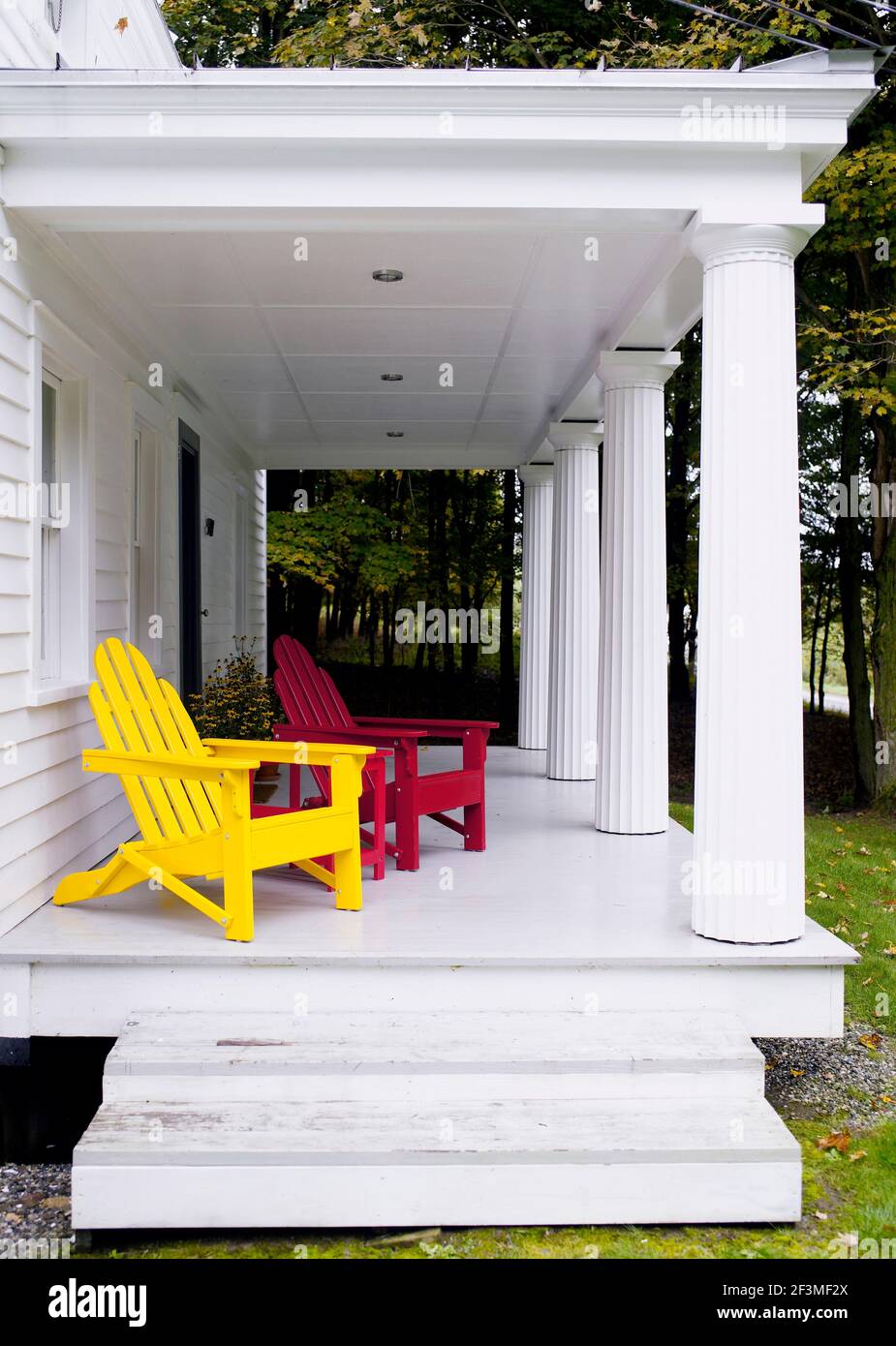 Sillas de madera rojas y amarillas en la veranda blanca en Larson, Nueva York, EE.UU Foto de stock