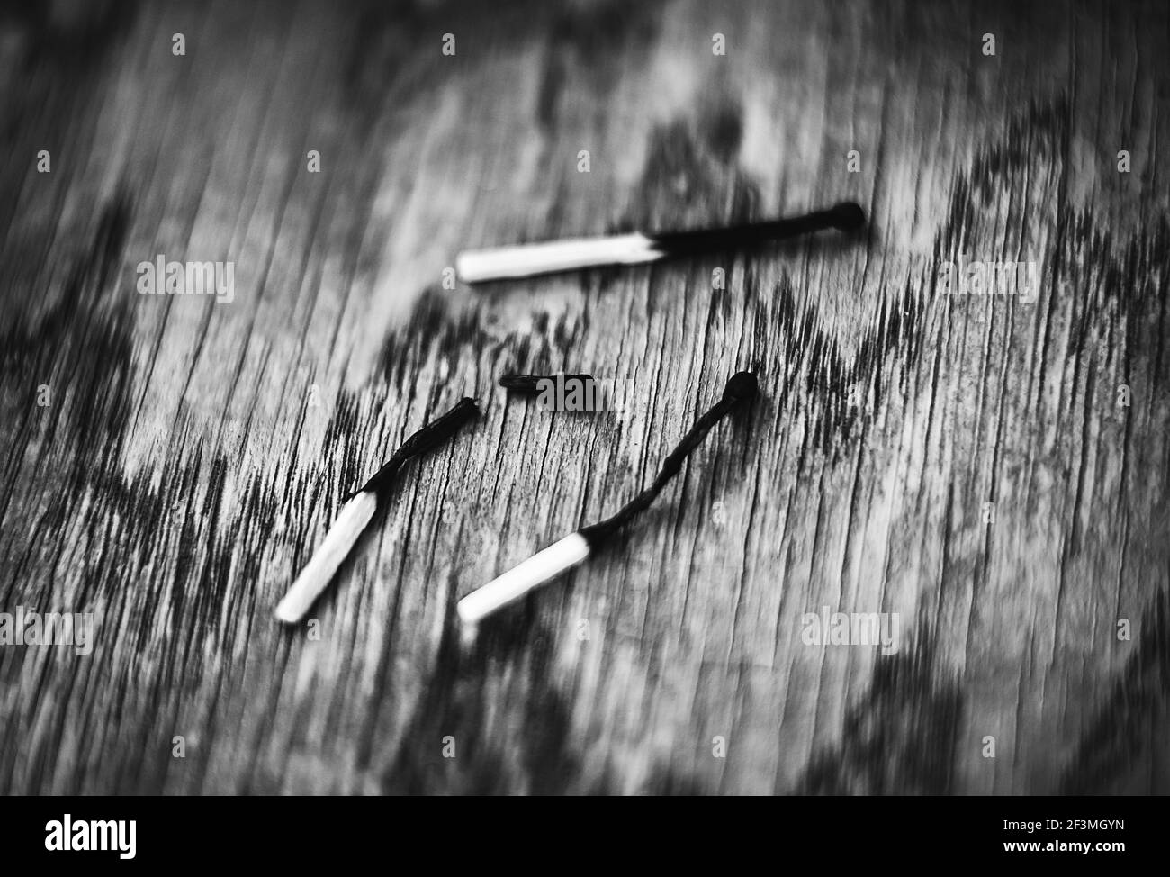 Una imagen en blanco y negro de tres partidos quemados sobre una mesa de madera. Uno de los partidos se quemó y se rompió. Peligro. Foto de stock