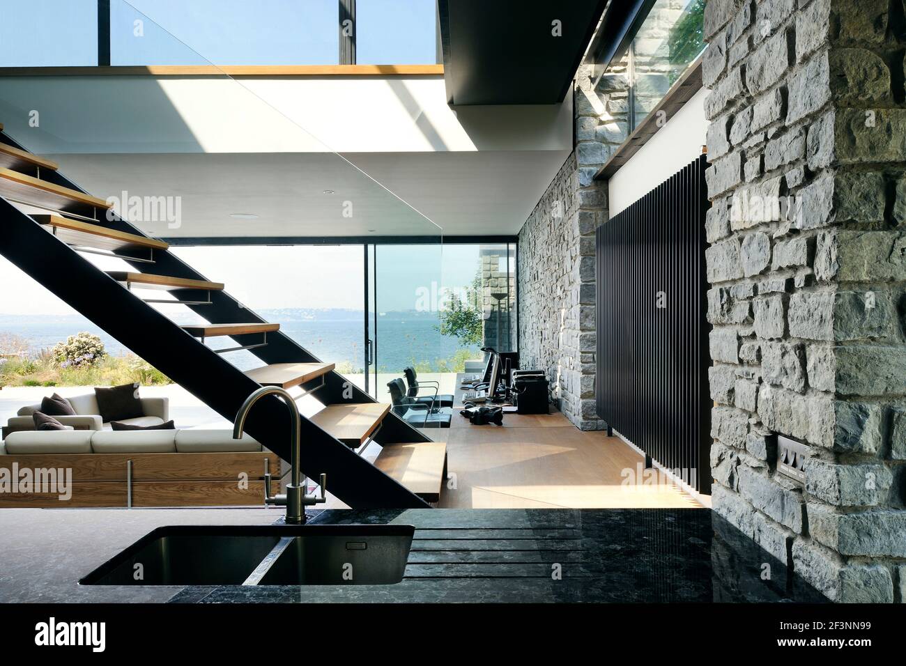 Los espacios interiores de una casa moderna en los acantilados con vistas  al mar. Grandes paneles y paredes de vidrio, y estantes de madera y  divisores de habitaciones. Flotando Fotografía de stock -