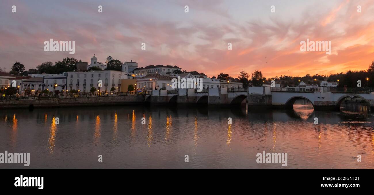 Puesta de sol sobre el puente romano a través del río Gilao en Tavira, Algarve Oriental, Portugal Foto de stock