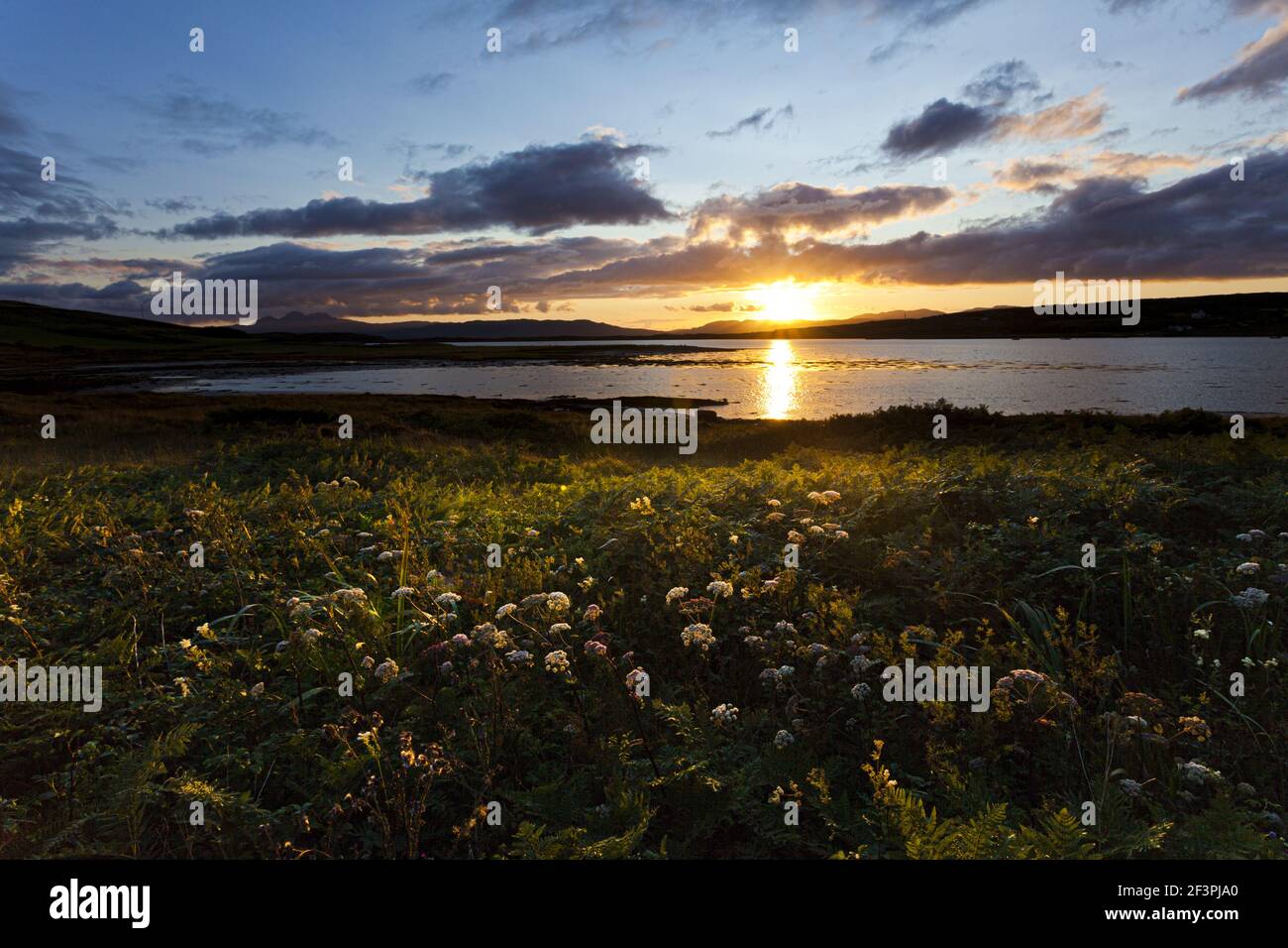 Una puesta de sol a través del lago na Cille a la península de Keillmore vista desde Danna, Knapdale, Argyll & Bute, Escocia, Reino Unido Foto de stock