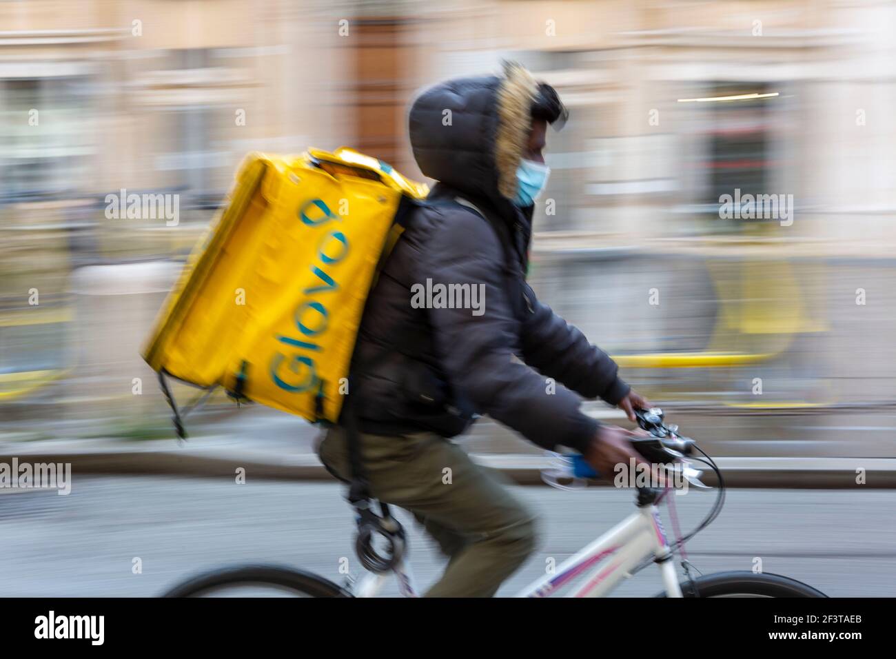 Foto borrosa con movimiento de entrega de alimentos en bicicleta Con caja  de Glovo termica amarilla en el tiempo de Covid Fotografía de stock - Alamy