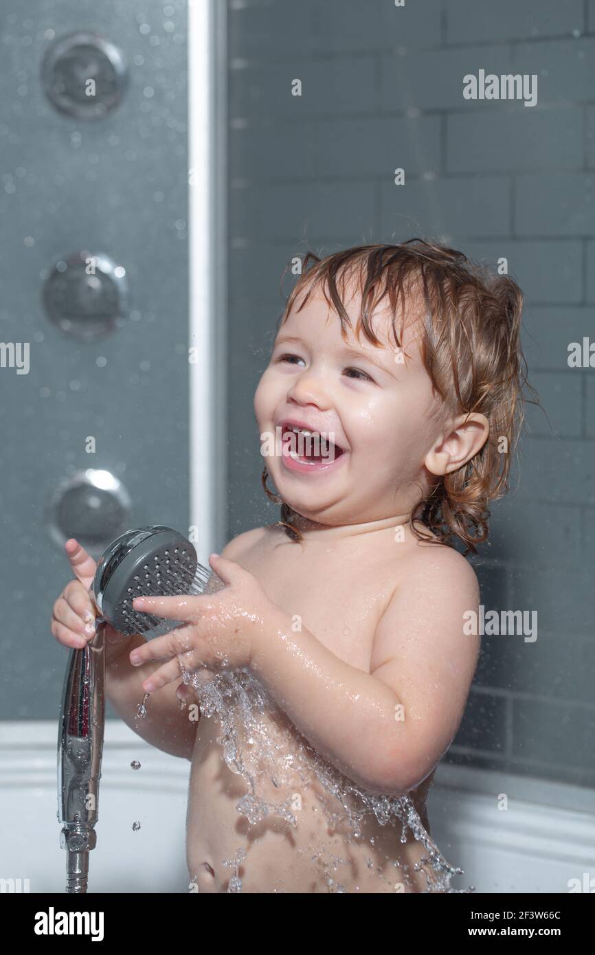 Niño bañándose bajo una ducha. Feliz bebé divertido bañado en el baño  Fotografía de stock - Alamy