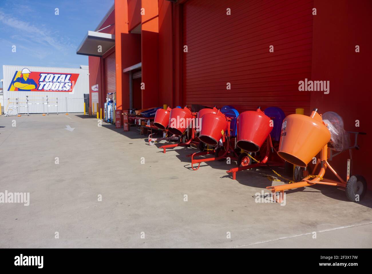Almacén total de herramientas para hardware y herramientas con una fila de mezcladores de cemento frente a una pared roja en Mackay, Queensland, Australia con espacio para copias. Foto de stock