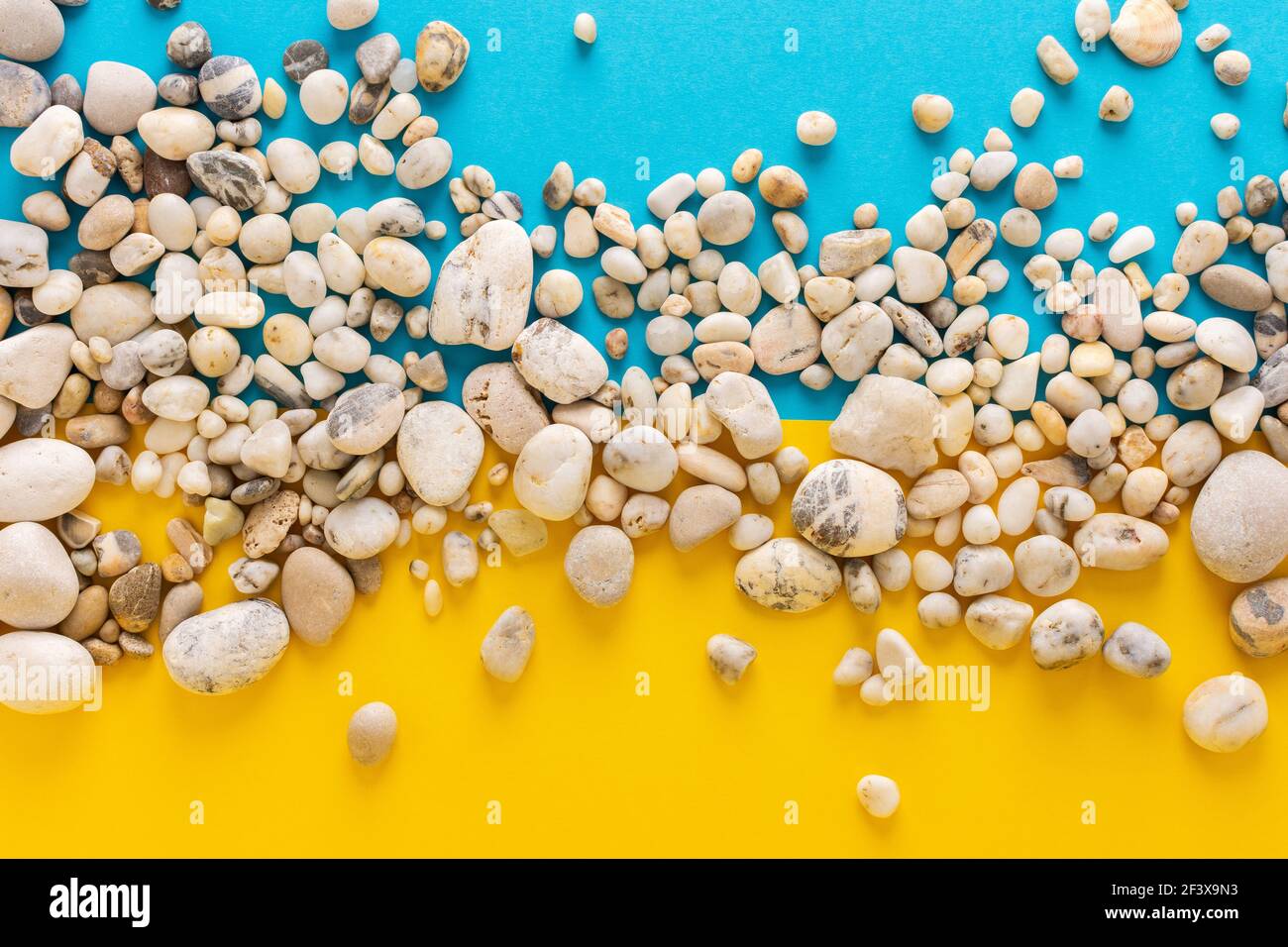 Introducir Intensivo George Bernard Piedras de luz marina sobre fondo azul y amarillo, espacio de copia,  vacaciones en el mar o el océano, fondo como arena con agua Fotografía de  stock - Alamy